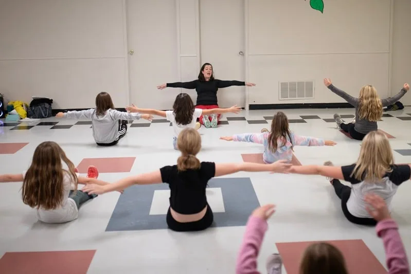 A class warming up together on the studio floor