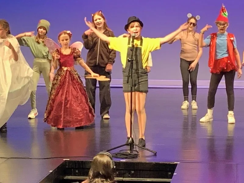 Ensemble Kids students in colourful costumes taking a bow on stage