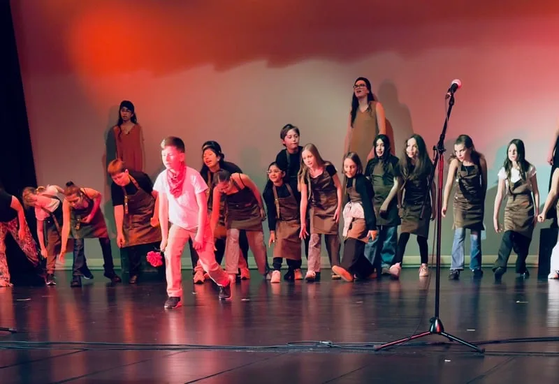 Students performing under red stage lights